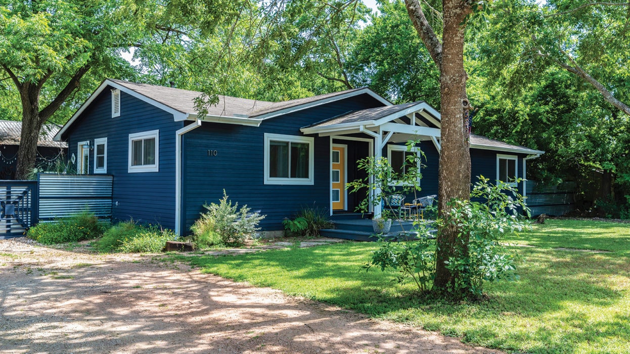Termite Control Service in Buda Blue house with a yellow door in Buda, Texas, surrounded by trees