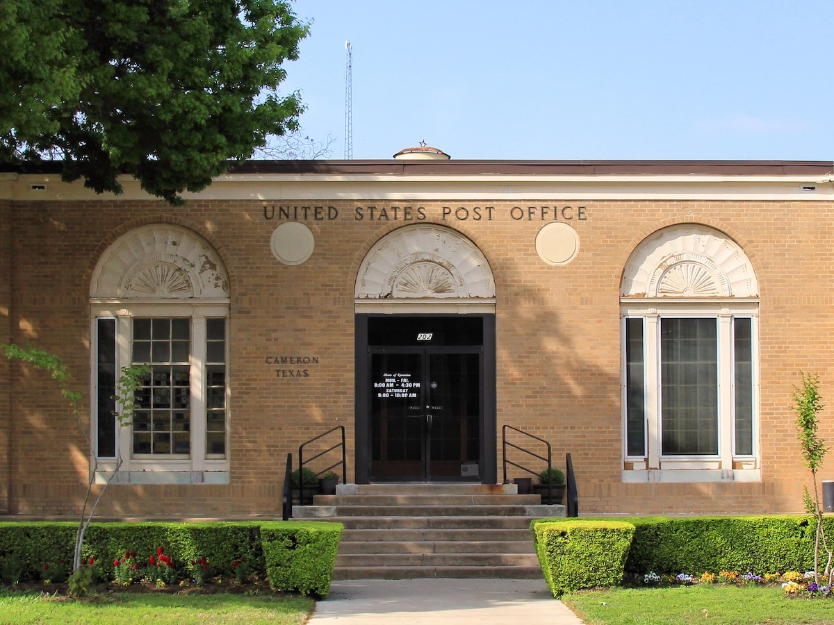 Termite Control Service in Cameron, Texas Historic United States Post Office building with stone details and a landscaped entrance