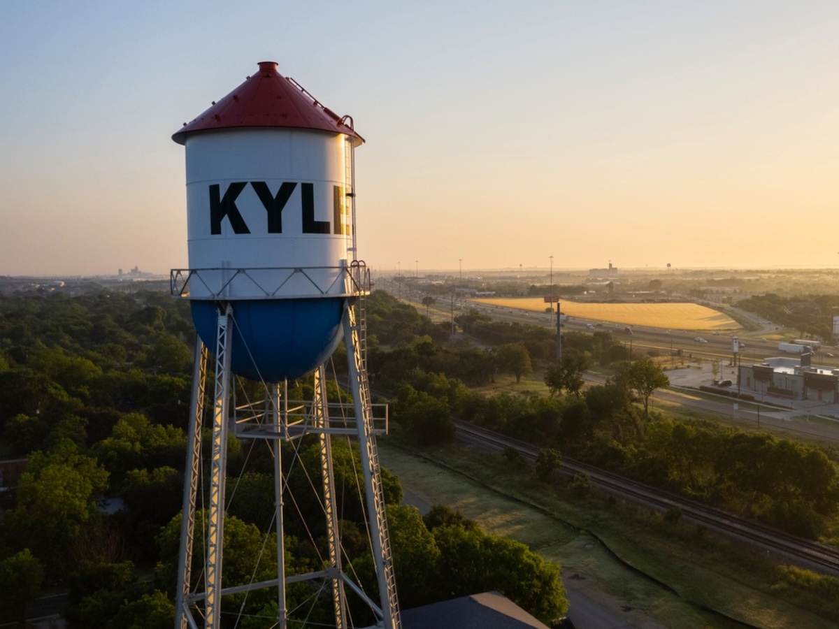 Termite Control Service in Kyle, Texas Aerial view of a water tower with the word 'KYLE' painted on it during sunset