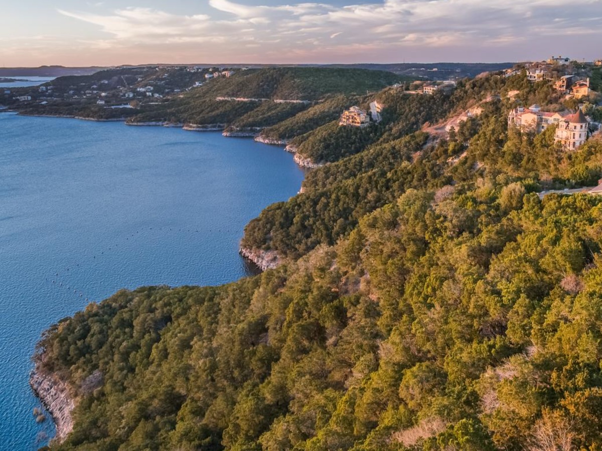 Termite Control Service in Lakeway, Texas Aerial view of lush green cliffs along a lake with hills in the distance