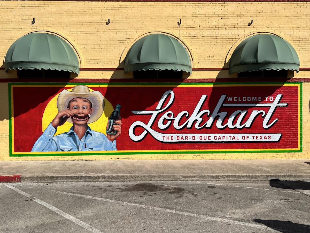 Termite Control Service in Lockhart, Texas Mural welcoming visitors to Lockhart, Texas, with a smiling cowboy and the phrase 'Bar-B-Q Capital of Texas