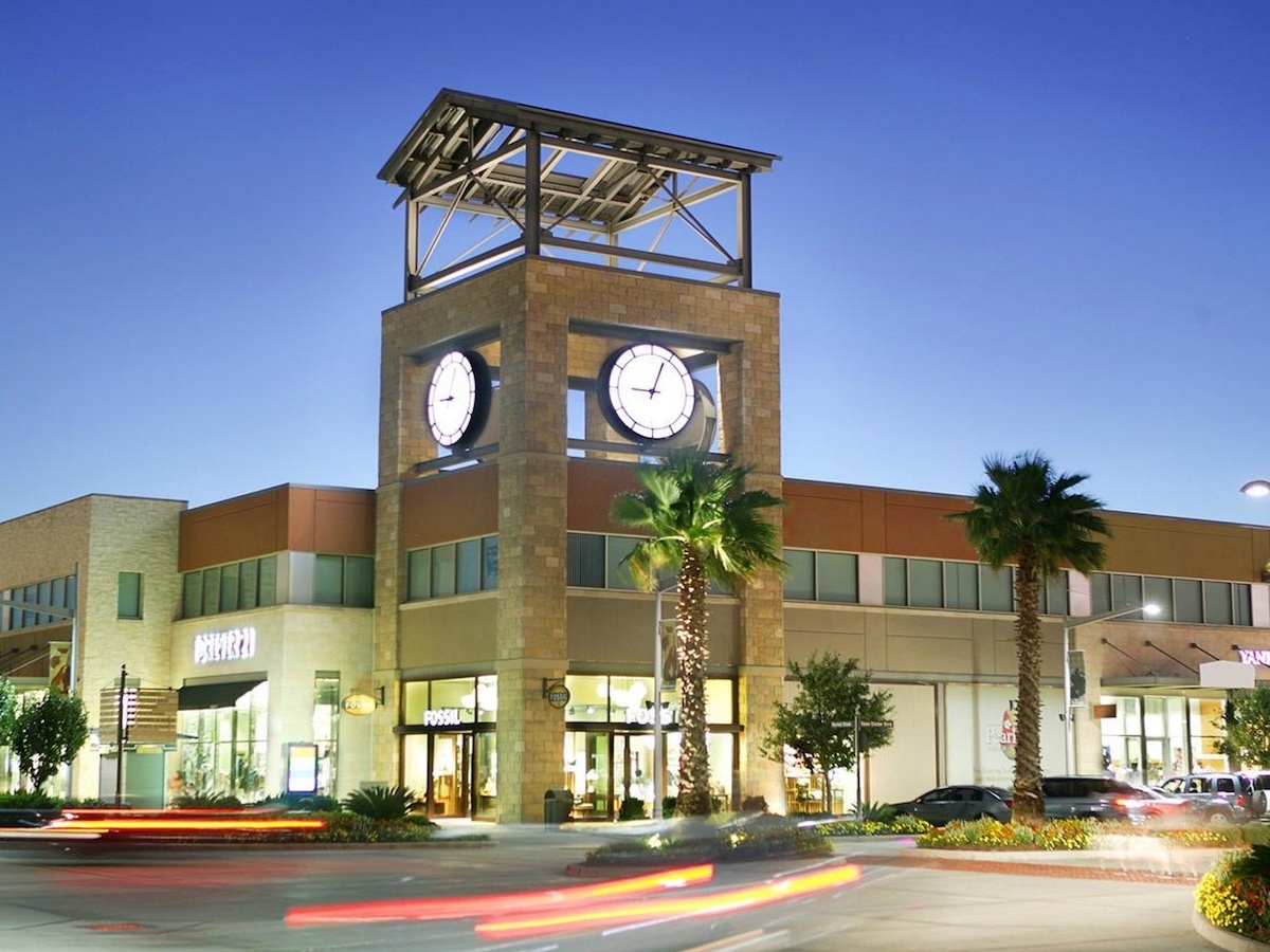Termite Control Service in Pearland, Texas Shopping center with a clock tower and palm trees at dusk