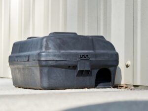 Rodent bait box placed along a building exterior wall, used by property managers to prevent rats and mice from entering commercial properties in Texas.